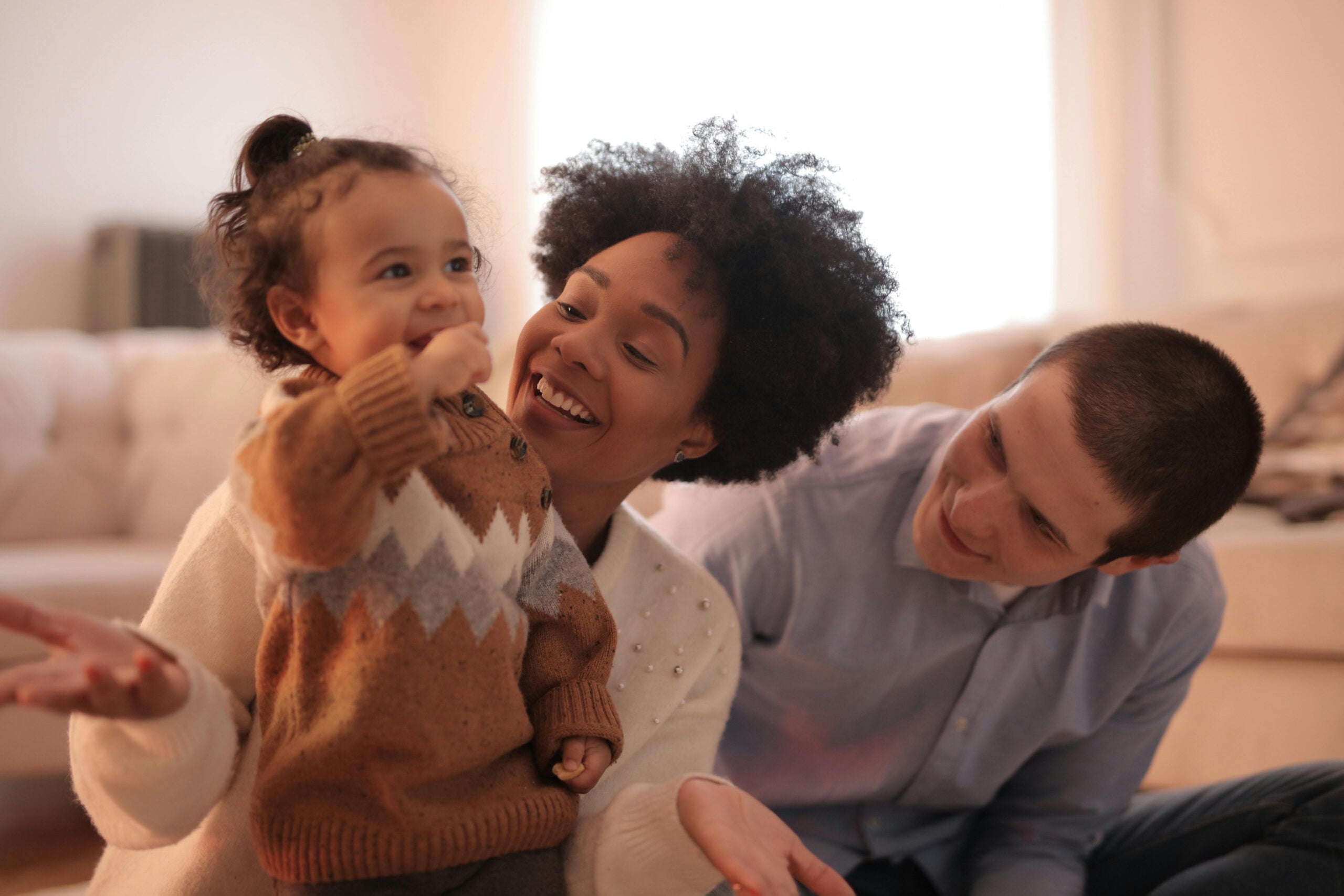 Man and woman smiling while holding their baby